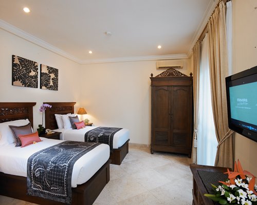 A well furnished bedroom with two beds and a television.
