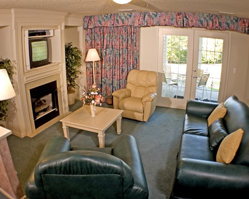 A well furnished living room with fireplace and television alongside the patio.