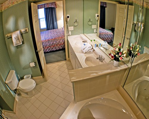 A bathroom with double sink and a bathtub alongside the bedroom.