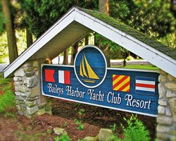 Signboard of the Baileys Harbor Yacht Club Resort alongside the trees.
