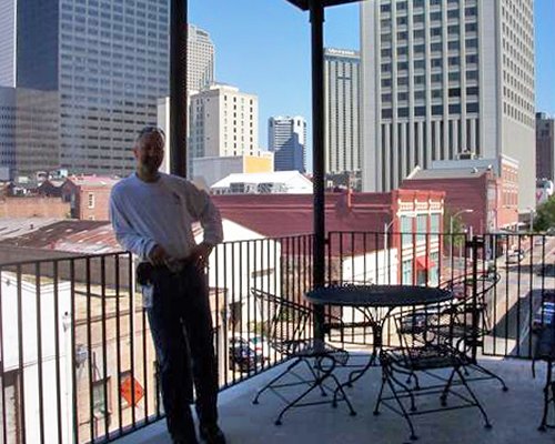 Man at the balcony with patio furniture and view of skyscrapers.