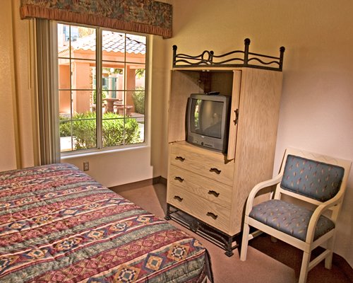 A well furnished bedroom with a television and outside view.
