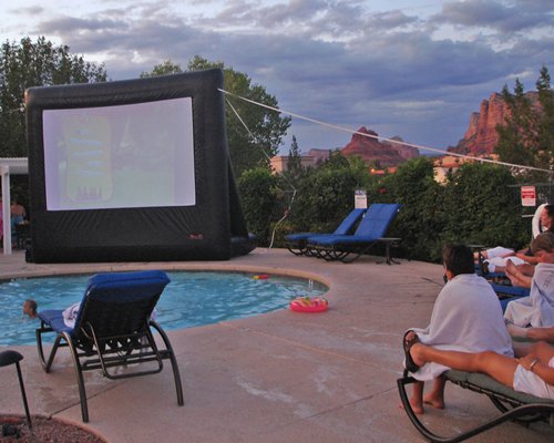 View of people watching a movie at the outdoor swimming pool with chaise lounge chairs.