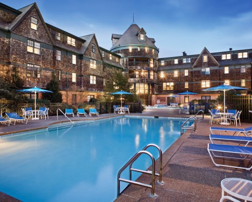 OUTDOOR SWIMMING POOL WITH CHAISE LOUNGE CHAIRS AND SUNSHADES ALONGSIDE THE UNIT.