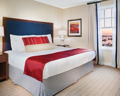 A WELL FURNISHED BEDROOM WITH A LAMP AND AN OUTSIDE VIEW.