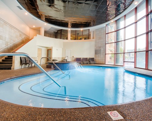 AN INDOOR SWIMMING POOL WITH AN OUTSIDE VIEW.