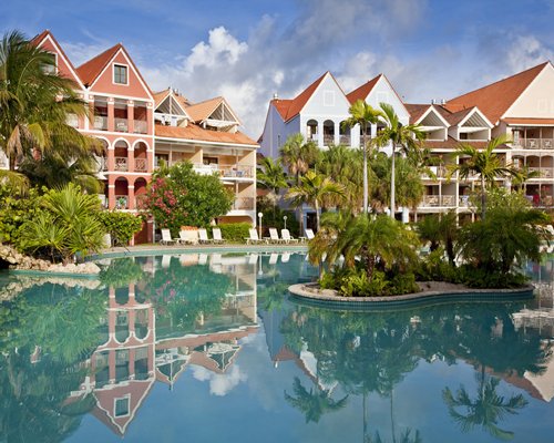 An outdoor swimming pool with chaise lounge chairs alongside the multi story units.