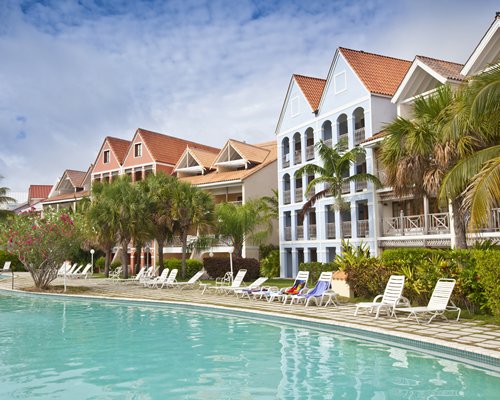 A view of an outdoor swimming pool with chaise lounge chairs alongside the resort.