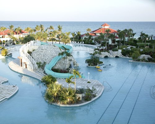 A large outdoor swimming pool with water slides surrounded by trees alongside the resort.