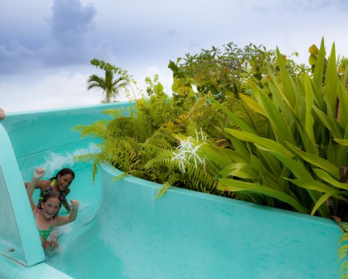 A view of two kids enjoying on a waterslide.