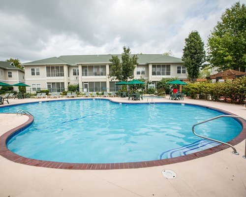 A view of an outdoor swimming pool with chaise lounge chairs alongside the resort units.