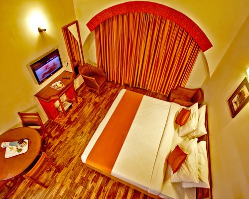 An aerial view of a well furnished bedroom with a double bed television and an outside view.