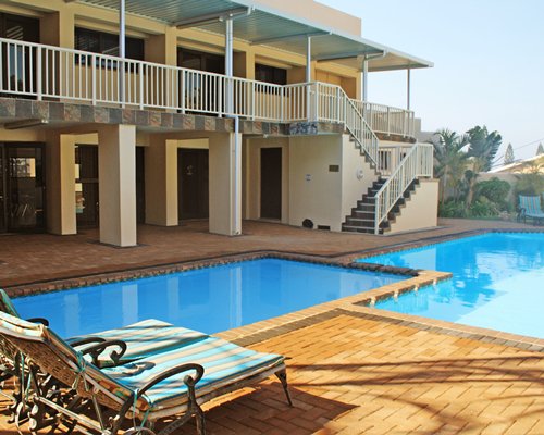 View of two outdoor swimming pool with chaise lounge chairs alongside multi story resort units.
