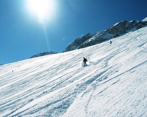View of man downhill skiing alongside the snowy mountain.