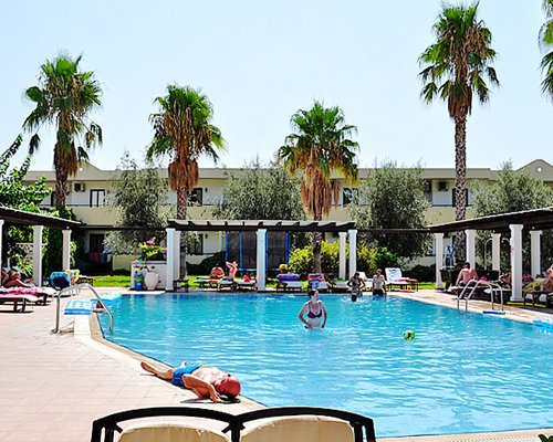 An outdoor swimming pool alongside resort units and palm trees.