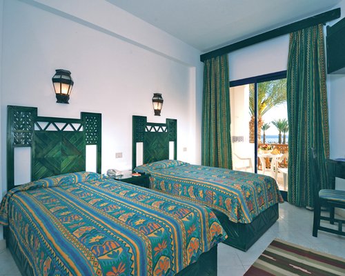 A well furnished bedroom with two twin beds and a balcony.