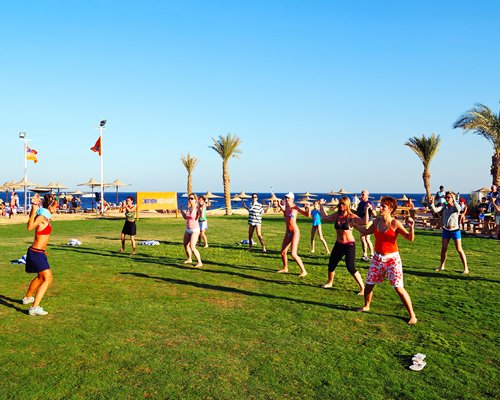 View of people exercising alongside the beach with sunshades and palm trees.