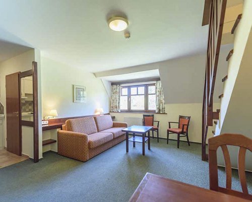 An open plan living and dining area with a double pull out sofa and staircase.