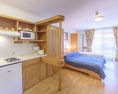 An open plan bedroom with a double bed kitchen and an outside view.