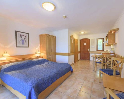 An open plan living room with a bed wooden dining and kitchen area.