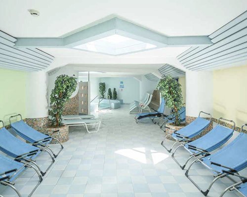 An indoor swimming pool with chaise lounge chairs.