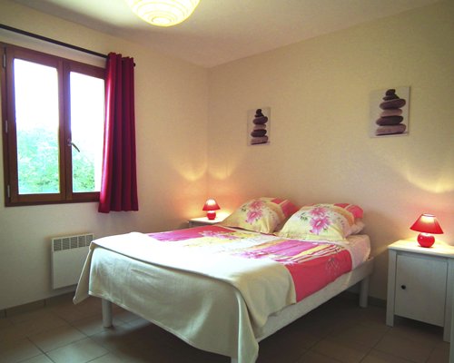 A furnished bedroom with a king bed and outdoor view.