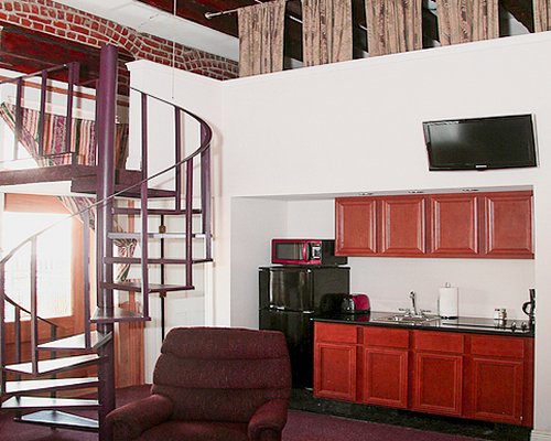 An open plan living and kitchen with a television alongside a spiral stairway.