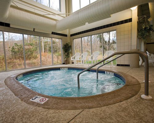 An indoor hot tub with patio furniture and an outside view.