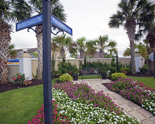 A direction board with flowering shrubs and palm trees.
