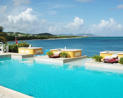 An outdoor swimming pool with chaise lounge chairs alongside the beach.