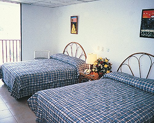 A well furnished bedroom with two double beds and an outside view.