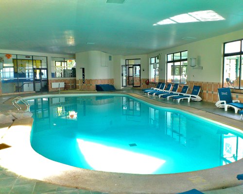 An indoor swimming pool with chaise lounge chairs.