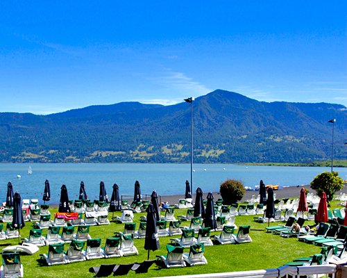 View of chaise lounge chairs in a well maintained lawn overlooking the beach and the mountains.