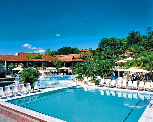 An outdoor swimming pool with chaise lounge chairs and trees alongside resort units.