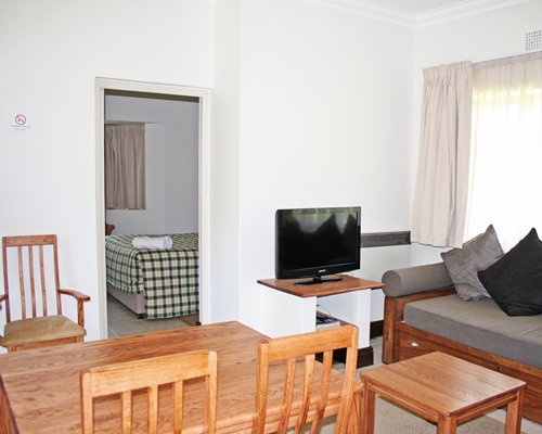 A well furnished living room with television dining area and bedroom with king bed.
