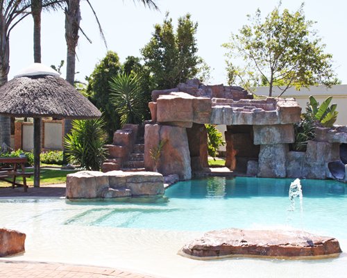 Outdoor grotto pool with fountain and picnic area.