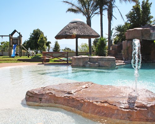 An outdoor pool with a thatched sunshade.