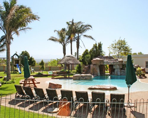 An outdoor swimming pool with chaise lounge chairs sunshades.