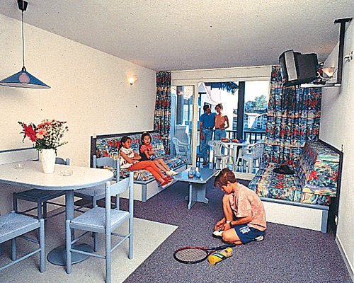 Family in a well furnished living room with television dining area and balcony.