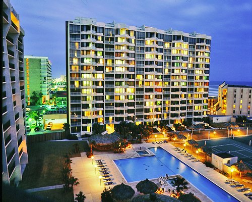An exterior view of the swimming pool alongside multi story units at night.