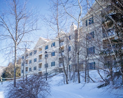 AN EXTERIOR VIEW OF MULTI STORY RESORT UNITS COVERED IN SNOW.