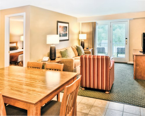 A WELL FURNISHED LIVING ROOM WITH TELEVISION DINING AREA OUTDOOR PATIO AND PATIO CHAIRS.
