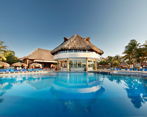 An outdoor swimming pool with chaise lounge chairs and a poolside bar.
