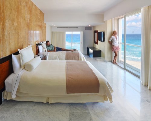 A well furnished bedroom with two beds and patio with an ocean view.