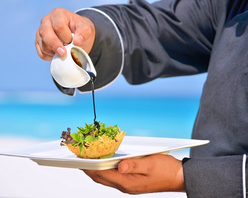 A man preparing a food item alongside the ocean.