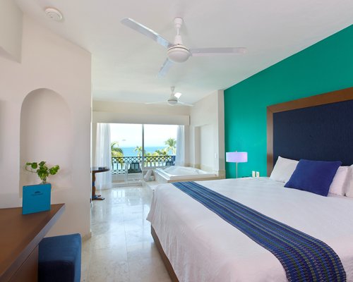 A well furnished bedroom with king bed bathtub balcony and bay view.
