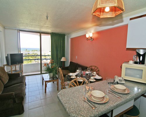 An open plan living and dining area with a television breakfast bar and balcony.