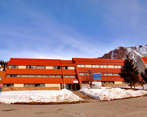 Exterior view of Geminis Apart Hotel alongside the mountains during winter.
