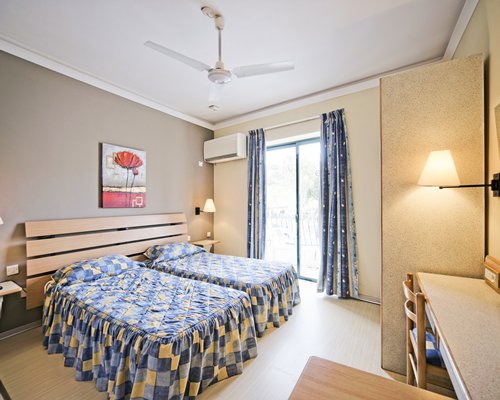 A well furnished bedroom with two twin beds and outdoor view.