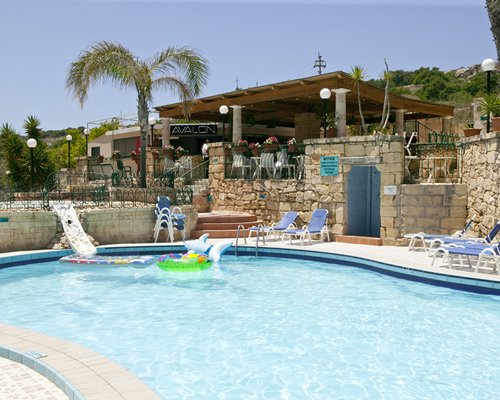 Outdoor swimming pool with chaise lounge chairs alongside a restaurant.
